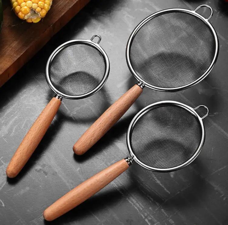 set-strecuratoare-inox-pe-blat-bucatarie.jpg Set de 3 strecurătoare inox de dimensiuni diferite pe un blat de bucătărie, pregătite pentru utilizare