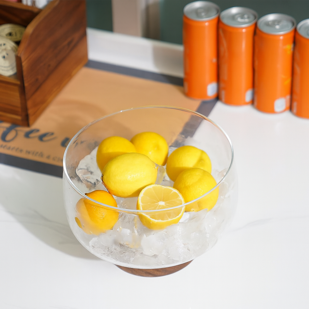 Bol din sticlă pe suport de lemn, plin cu lămâi așezate pe gheață