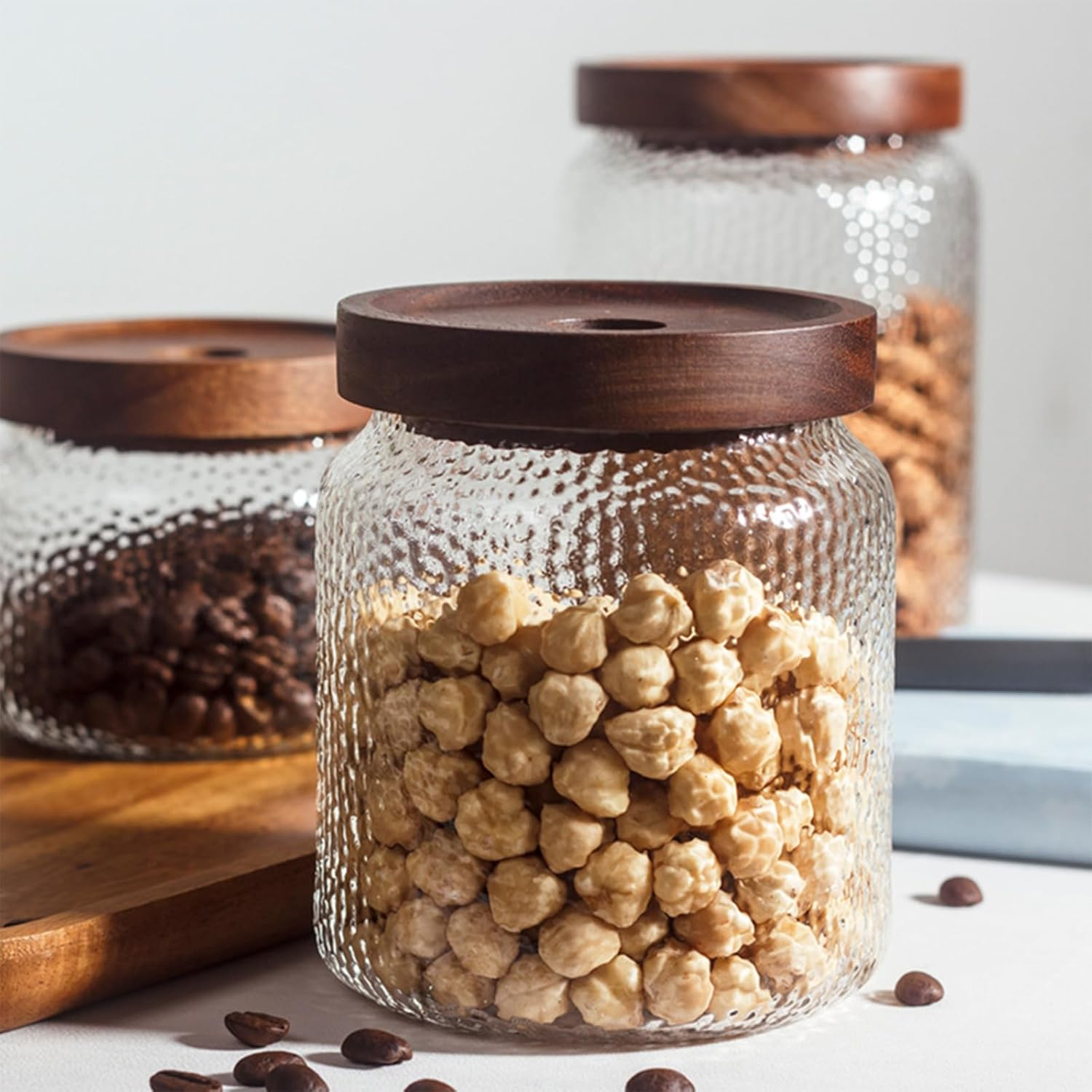 Borcane anti-alunecare cu capac etanș din lemn, umplute cu alune de pădure și cafea Borcane anti-alunecare cu capac etanș din lemn, umplute cu alune de pădure și cafea, ideale pentru depozitare.