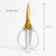 Foarfecă aurie cu mânere transparente, dimensiuni 20.5 cm înălțime și 9.5 cm lățime, greutate 108 g