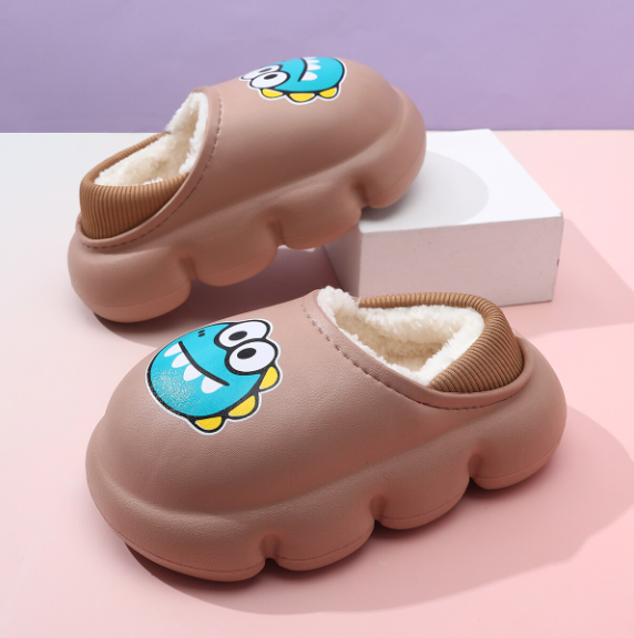 Papuci de iarnă pentru copii maro cu imprimeu monstrulet albastru și interior îmblănit, prezentați pe fundal roz și mov